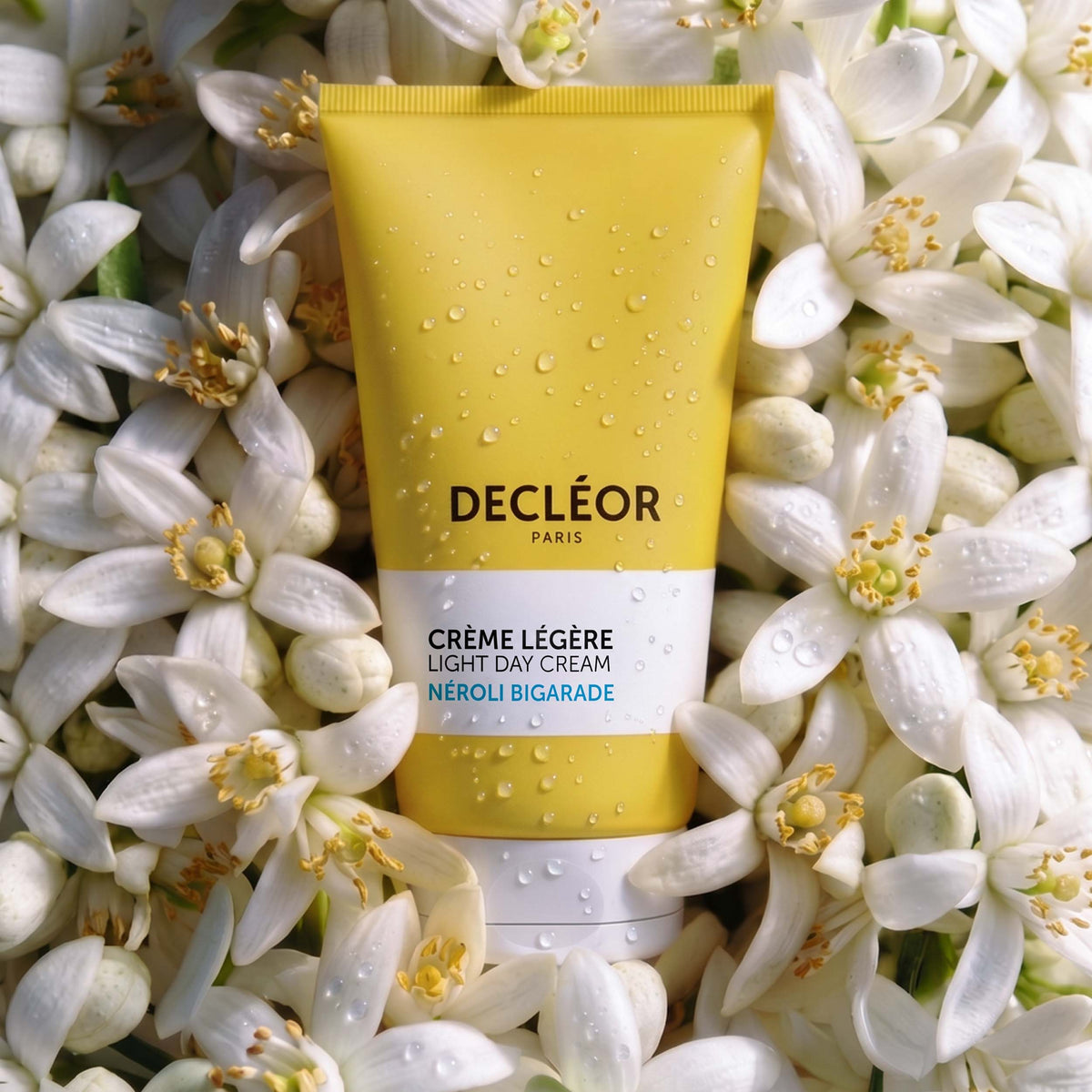 Tube of Light Cream Neroli Bigarade resting on orange blossoms